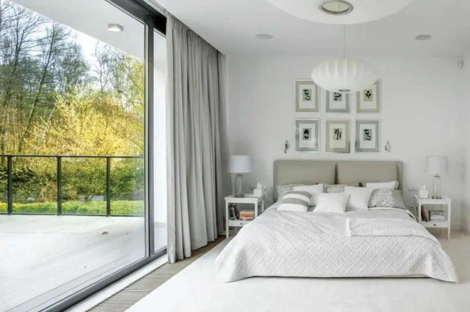 Бело-серый интерьер спальни подчеркивает панорамное окно